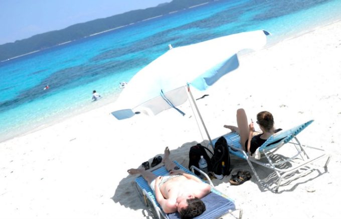 ビーチで寝転んでくつろぐ外国人観光客
