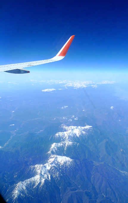 飛行機の窓から雪を被った山脈が見える風景