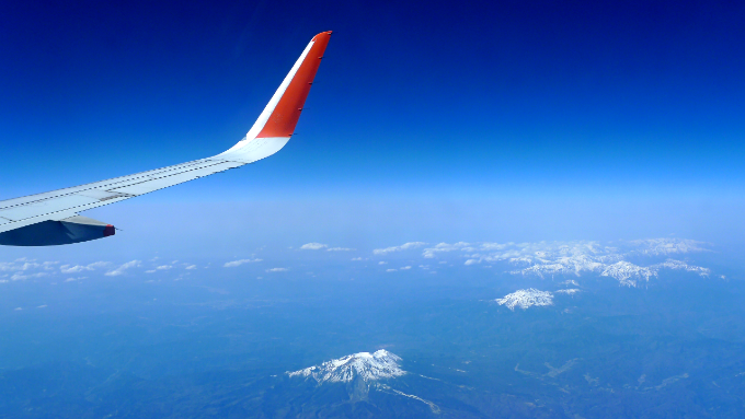 飛行機の窓から雪を被った山脈が見える風景